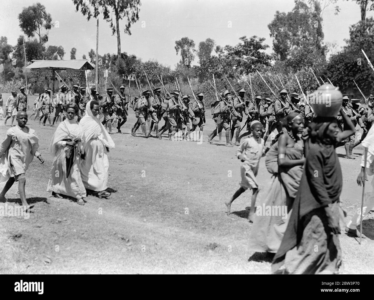 La fanteria regolare dell' esercito di Ras Nasibu lasciò Harar per Jijiga sulla strada verso il fronte meridionale per rinforzare l' esercito meridionale di Ras Desta , che si riferisce abbia respinto gli italiani . In primo piano , i parenti possono essere visti seguendo le truppe fuori città . 27 novembre 1935 Foto Stock