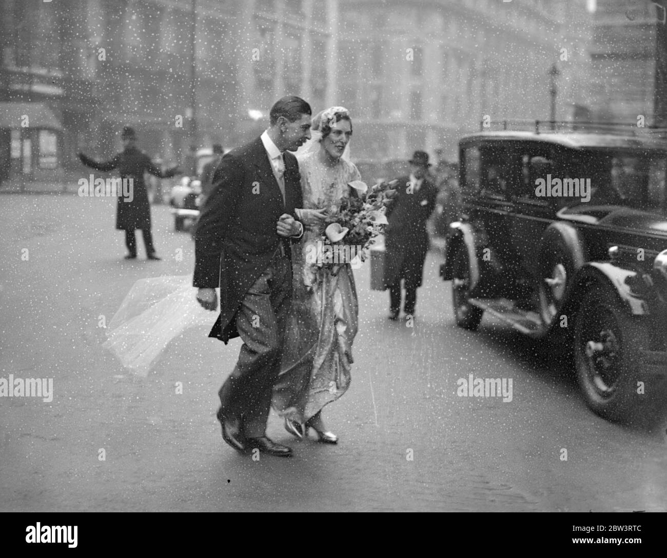 Processione nuziale attraverso Langham luogo dopo tutte le anime matrimonio . Dopo il loro matrimonio alla Chiesa di All Souls , Langham Place , W , capitale Victor Paley della brigata del fucile , e la sua sposa , forma Miss Susan Paine , camminarono per la strada con il loro retinue al Langham Hotel , dove si svolse la reception . Spettacoli fotografici , la processione nuziale che attraversa la strada le accanto allo sposo e sposa . 14 aprile 1936 Foto Stock