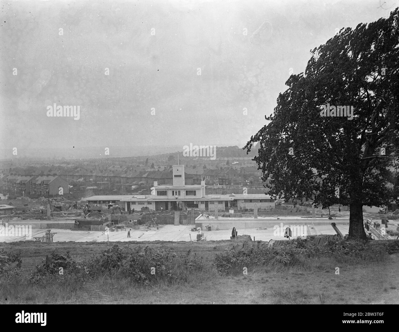 La piscina sul pendio di Chingford è quasi pronta. La nuova piscina di Chingford a Larkswood è in fase di completamento e sarà aperta da Sir Kingsley Wood , Ministro della Sanità , tra un periodo di due settimane . La piscina è in fase di costruzione su un sito di sette ettari di bosco. Poiché si trova sul lato di una collina, migliaia di tonnellate di terra dovevano essere rimosse . La sua posizione protegge dal vento e ha la massima quantità di sole . L'area della piscina e' di 2700 iarde quadrate, con una lunghezza di nuoto di 165 piedi e una larghezza di 60 piedi. Ha un cafe, terrazze sunn e edifici amministrativi. Punto Foto Stock