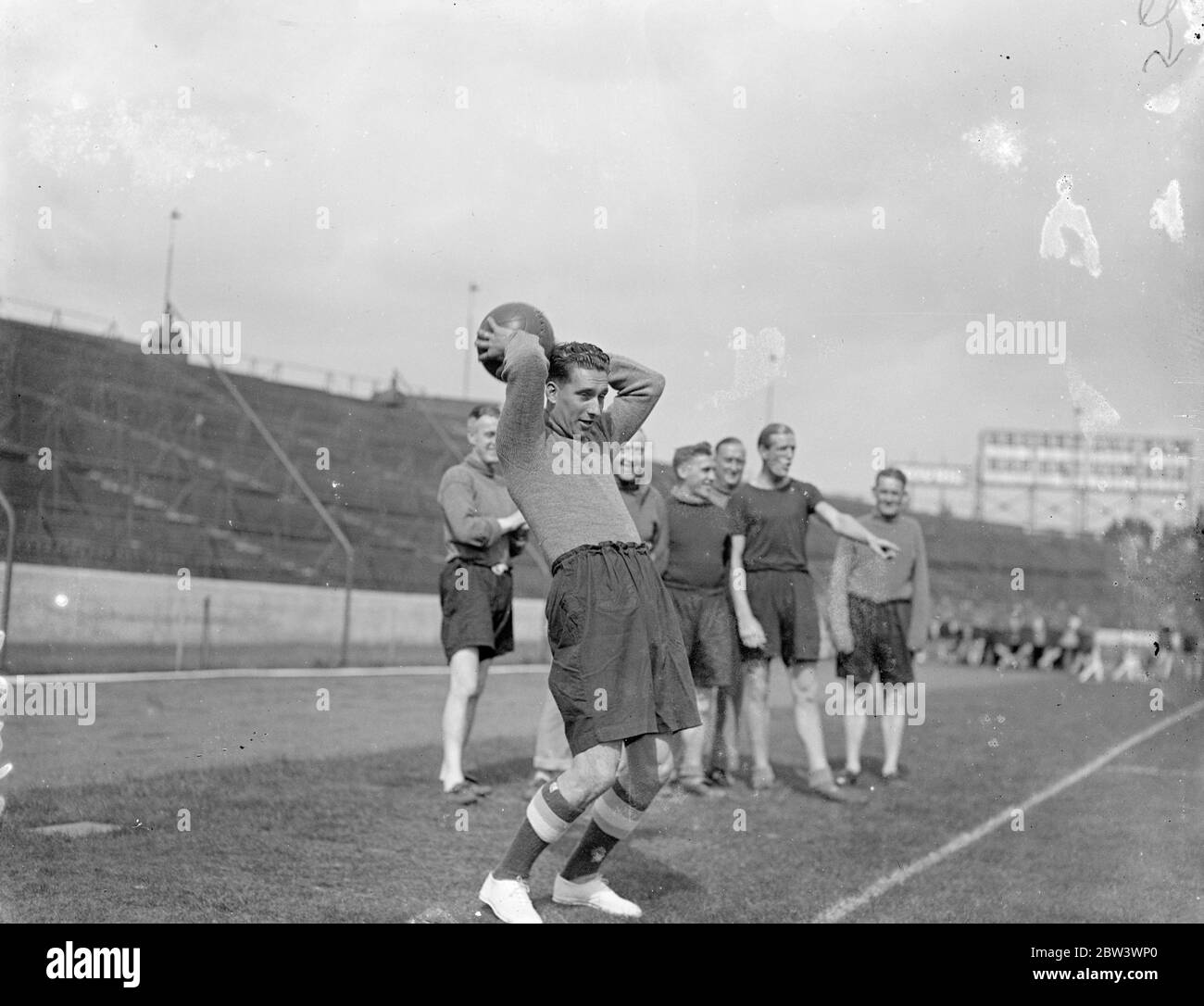 Sam Weaver , ora giocatore di Chelsea , dimostra il suo famoso ' tiro in ' può lanciare la palla da touchline a goalpost , Sam Weaver , il Newcastle United e Inghilterra ha lasciato il mezzo di ritorno che è stato trasferito a Chelsea , si è Unito alla sua nuova squadra al ponte di Stamford , Londra , terra . Weaver capitanò Newcastle la scorsa stagione , facendo 31 apparizioni di campionato . Nel 1932 fu chiuso contro la Scozia e nel 1933 contro la Scozia e l'Irlanda. Foto , Sam Weaver dimostra il suo fenomenale ' lancio in ' due membri della sua nuova squadra a Stamford Bridge . 14 agosto 1936 Foto Stock