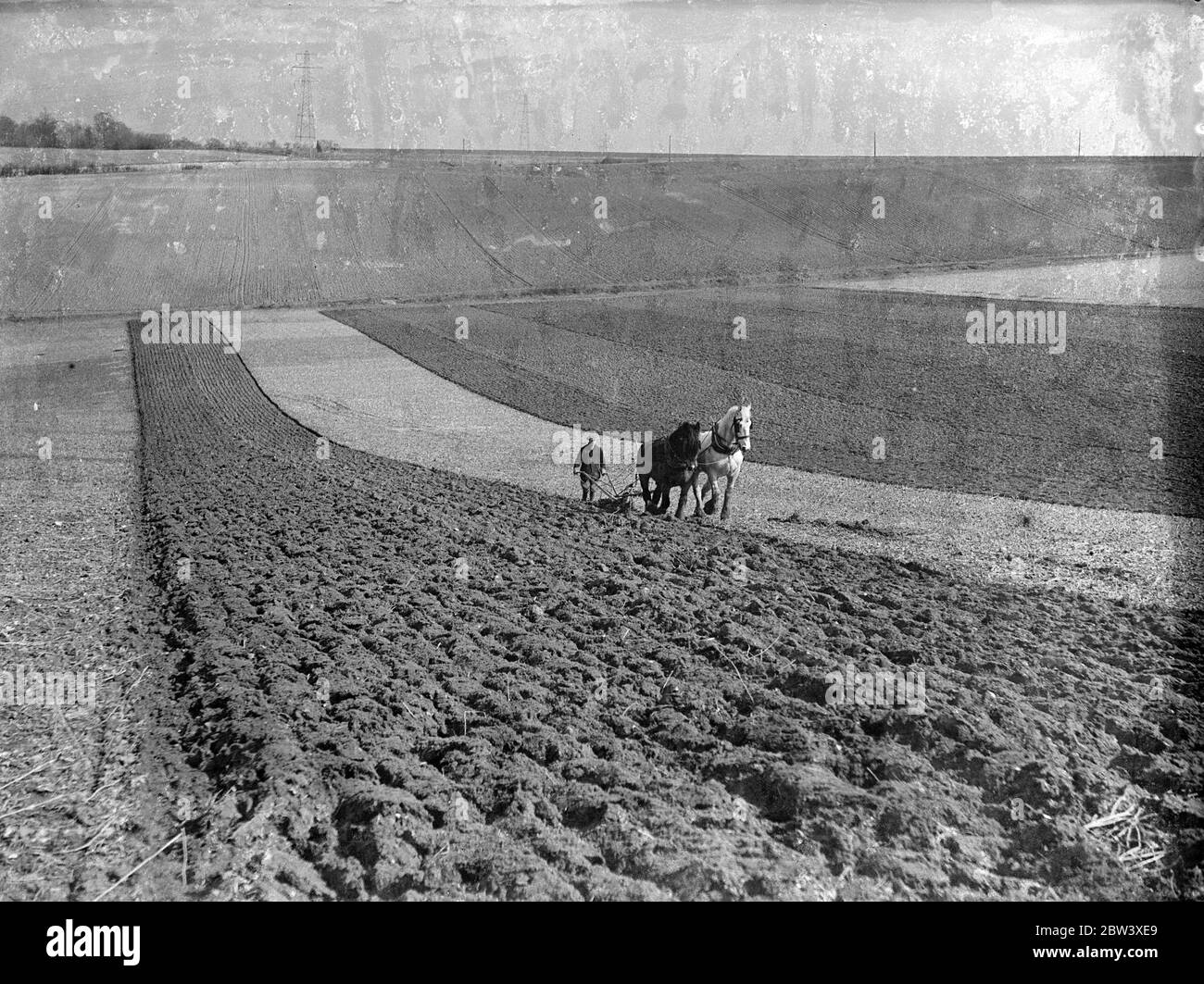 Mentre le nubi volute della primavera iniziale si sono radunate verso la sera, il pagliaio segue dietro la sua squadra robusta mentre gira gli ultimi solchi della ricca terra di Kentish sugli ampi acri di una fattoria di Farningham . 25 marzo 1937 Foto Stock