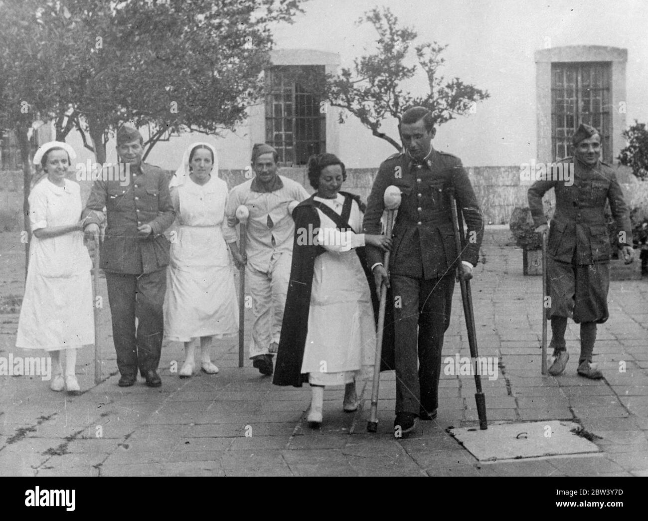 Giovani infermieri della Spagna dei ribelli. Allegro guerra facoltà di convanescenza . Sebbene gravemente feriti e paralizzati dalla guerra civile , questi soldati ribelli delle forze di Franco trovarono la loro convalescenza resa più facile dalla allegra e sorridente presenza dell' ordinato , Infermieri bianchi in uniforme mentre si sono scesi quotidianamente in grondate in un ospedale di base dei ribelli in Spagna . Molte giovani donne stanno servendo come infermieri presso gli ospedali di emergenza e le basi di pronto soccorso stabilite in vista della linea di primo soccorso . 8 marzo 1937 Foto Stock