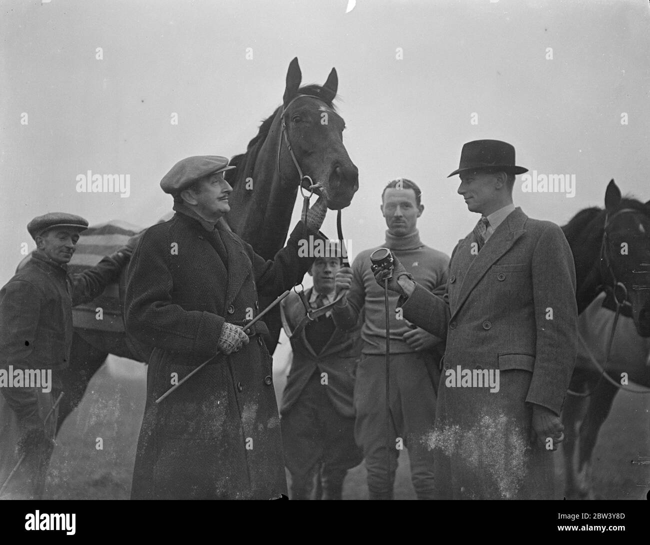 Tom Walls e cavalli offrono effetti per la trasmissione della funzione Grand National. Tom Walls, l'attore del film, e i cavalli da corsa che ha addestrato al Looe, Ewell, Surrey, ha fornito un furgone di registrazione della BBC con i rumori che richiedono per illuminare l'occhio del programma di Grand National Feature che è chiamato direttamente dalla bocca del Cavallo. Tom Walls è il capo della trasmissione, preparando tutto per la BBC. Sta consegnando la sua tassa al Fulham Road Cancer Hospital. Foto: Tom Walls, suo figlio, Tom Walls Jr., tenendo Lad spinoso che parla nel microfono per un ingegnere BBC. 5 Mar Foto Stock