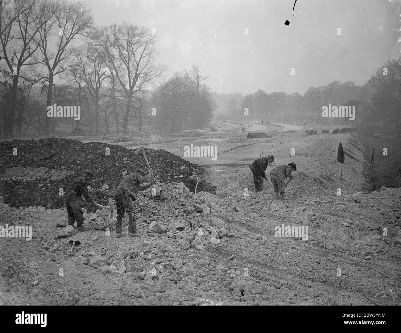 Scavo per il nuovo ponte per il trasporto di un nuovo bypass Surrey - 100 piedi di larghezza. Gli ingegneri che lavorano alla nuova tangenziale di Mickleham stanno costruendo un nuovo ponte stradale lungo l'esistente Burford Bridge sul fiume Mole vicino a Dorking, Surrey. Il vecchio ponte sarebbe demolito quando la nuova struttura larga cento piedi, che porterà il bypass, è completata. Foto: Scavi sulla riva del fiume Mole per le fondamenta del nuovo ponte vicino Dorking, Surrey. 19 gennaio 1937 Foto Stock