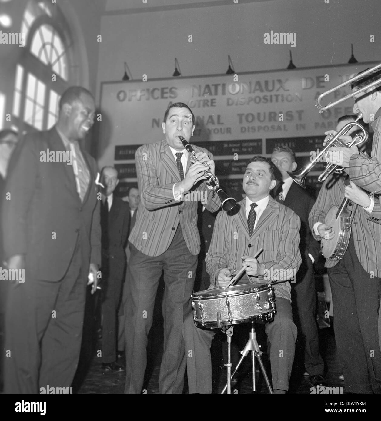 Louis Armstrong a Parigi . Il Re del jazz , il violentato Louis Armstrong e la sua orchestra sono arrivati questa mattina a Parigi da Abidjan , nell'ultimo passo del suo viaggio dall'Africa . Louis Armstrong e' a Parigi per apparire in ' Paris Blues' accanto a Paul Newman , Joanne Woodward e Sydney Poitier , sotto la direzione di Martin Ritt . Dopo il loro arrivo da Orly qui sono Louis Armstrong e Velma Middleton circondati dai musicisti della Mowgli Jospin High Society Jazz Band che sono venuto a suonare all'aeroporto di Parigi . 5 dicembre 1936 Foto Stock