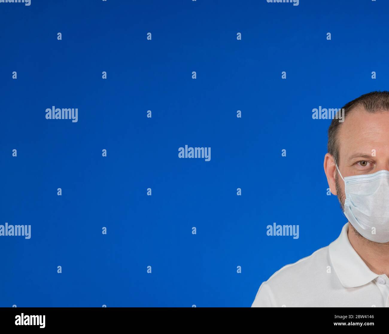 Uomo isolato indossando maschera protettiva su sfondo blu e con ampio spazio per la copia. Concetto di problema di salute, misura preventiva contro Coronavirus Foto Stock