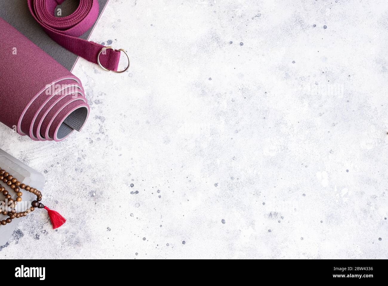 Accessori per yoga. Tappeto per esercizi arrotolati, perline di legno mala, blocchi yoga e cintura su fondo grigio in cemento. Yogi è un'attività di sostegno essenziale per la pratica e per il m. Foto Stock