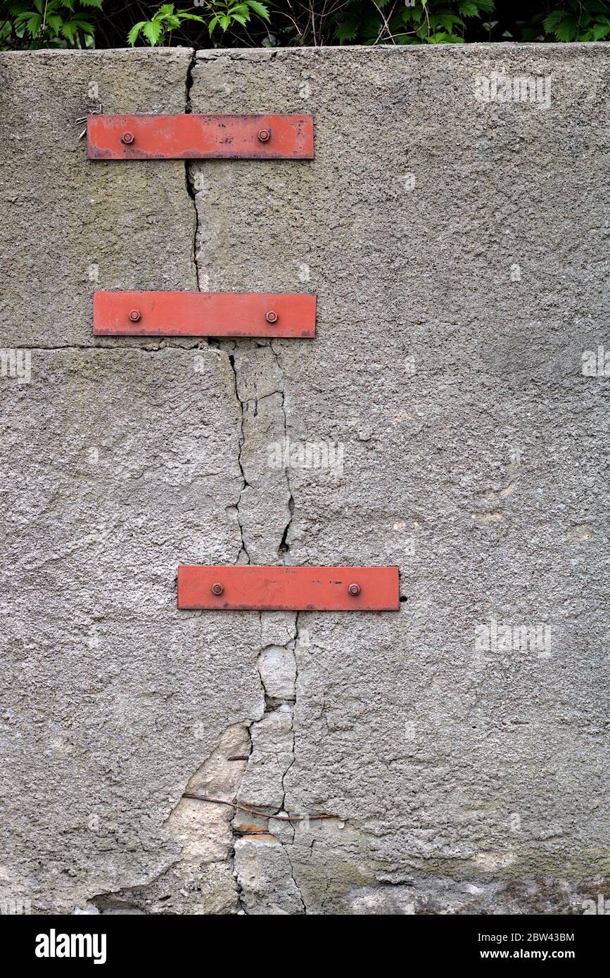Parete incrinata collegata da elementi metallici. Foto Stock