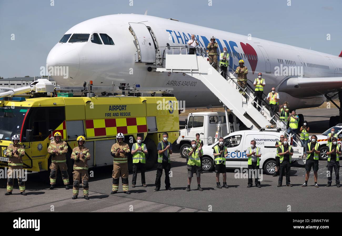 L'equipaggio di un volo del gruppo europeo dell'aviazione, che sta per partire per la Cina per raccogliere i DPI, si trova di fronte al proprio aereo all'aeroporto internazionale di Bournemouth, accanto al personale e ai vigili del fuoco dell'aeroporto di Bournemouth; Come si uniscono negli applausi per salutare gli eroi locali durante il Clap nazionale di Giovedi per i caregivers di riconoscere e sostenere i lavoratori e gli assistenti NHS che combattono la pandemia del coronavirus. Foto Stock