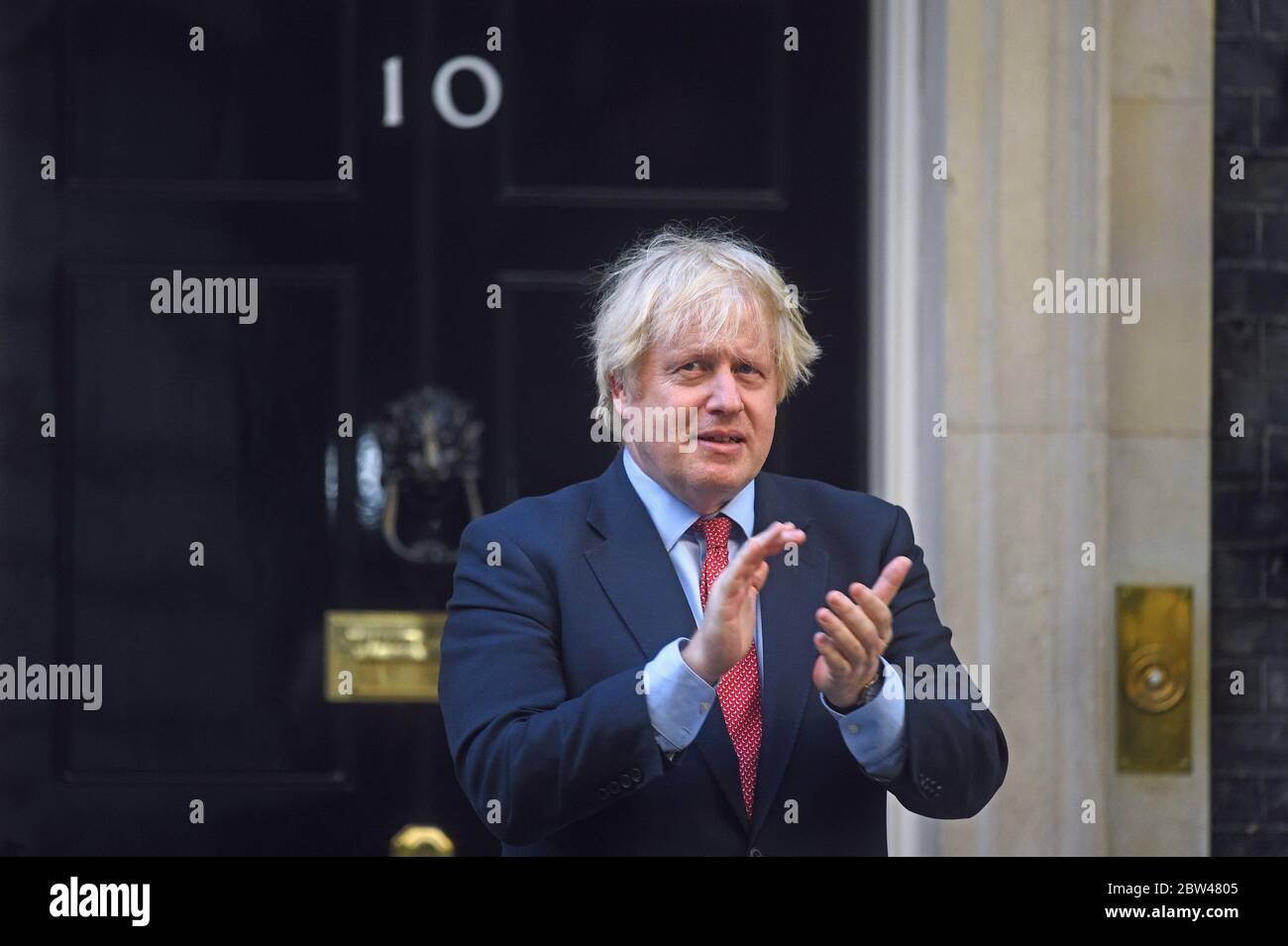 Il primo Ministro Boris Johnson entra a far parte del settimanale Clap for Carers al di fuori della sua residenza ufficiale di Londra a Downing Street. Foto Stock