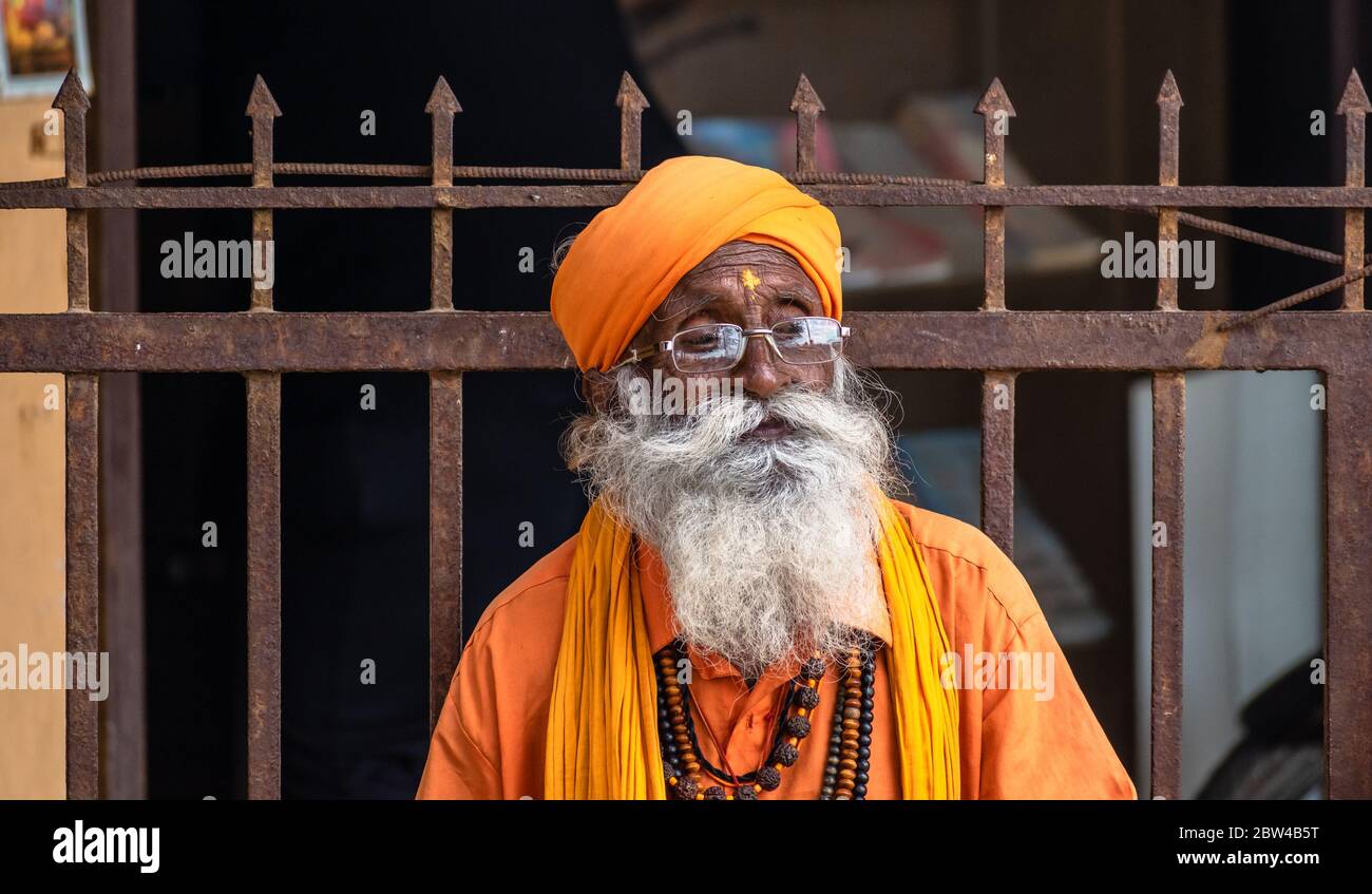 Somnath, Gujarat, India - Dicembre 2018: Un ritratto candido di un anziano monaco indù vestito con un abito e un turbante di zafferano con un'espressione premurosa Foto Stock