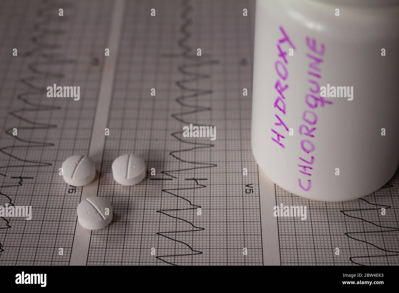 Effetti avversi sul cuore da parte di idrossiclorochina o clorochina. Pillole su un elettrocardiogramma con aritmie cardiache. Contenitore bianco con 'idro Foto Stock