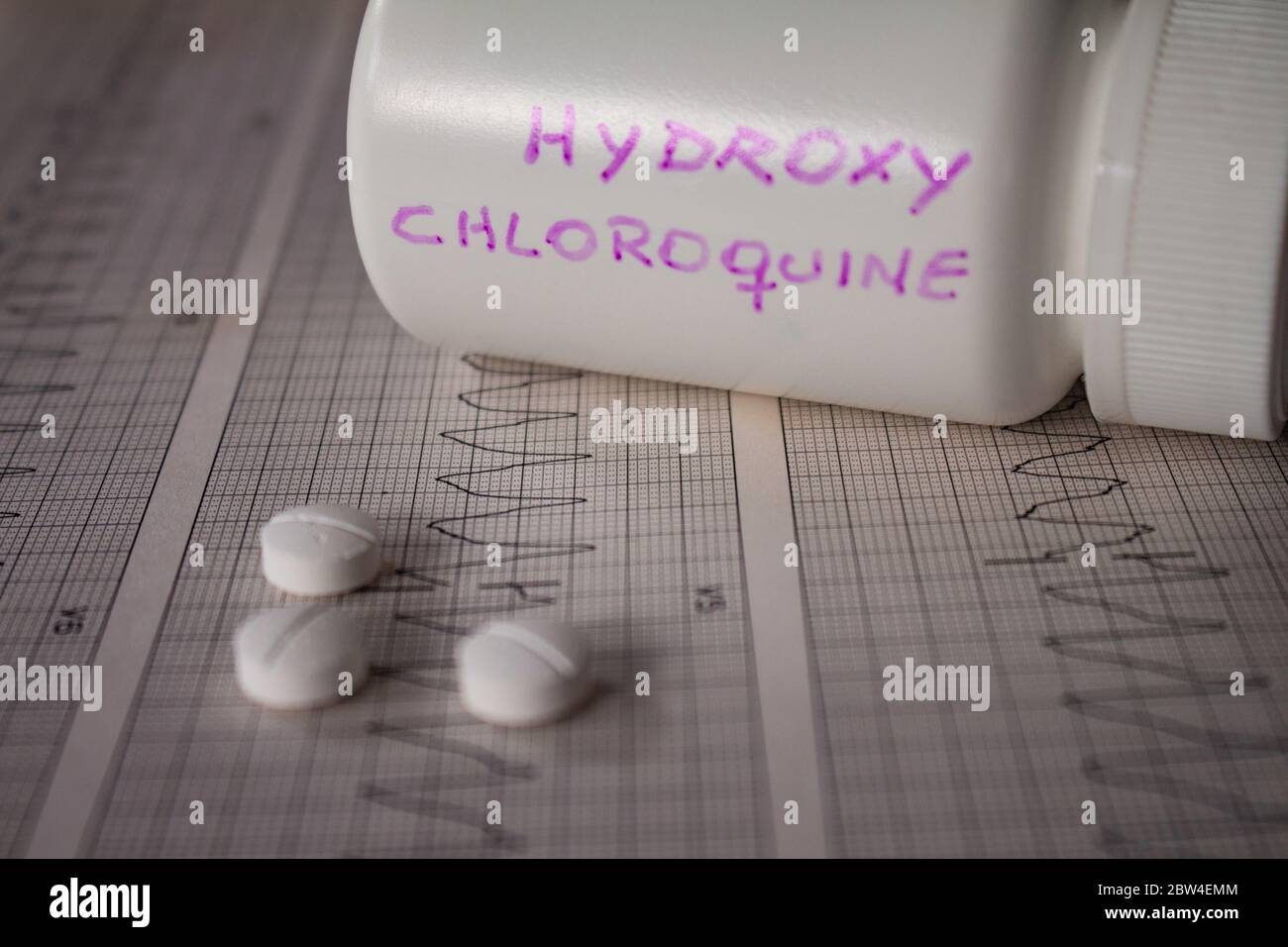 Effetti avversi sul cuore da parte di idrossiclorochina o clorochina. Pillole su un elettrocardiogramma con aritmie cardiache. Contenitore bianco con 'idro Foto Stock