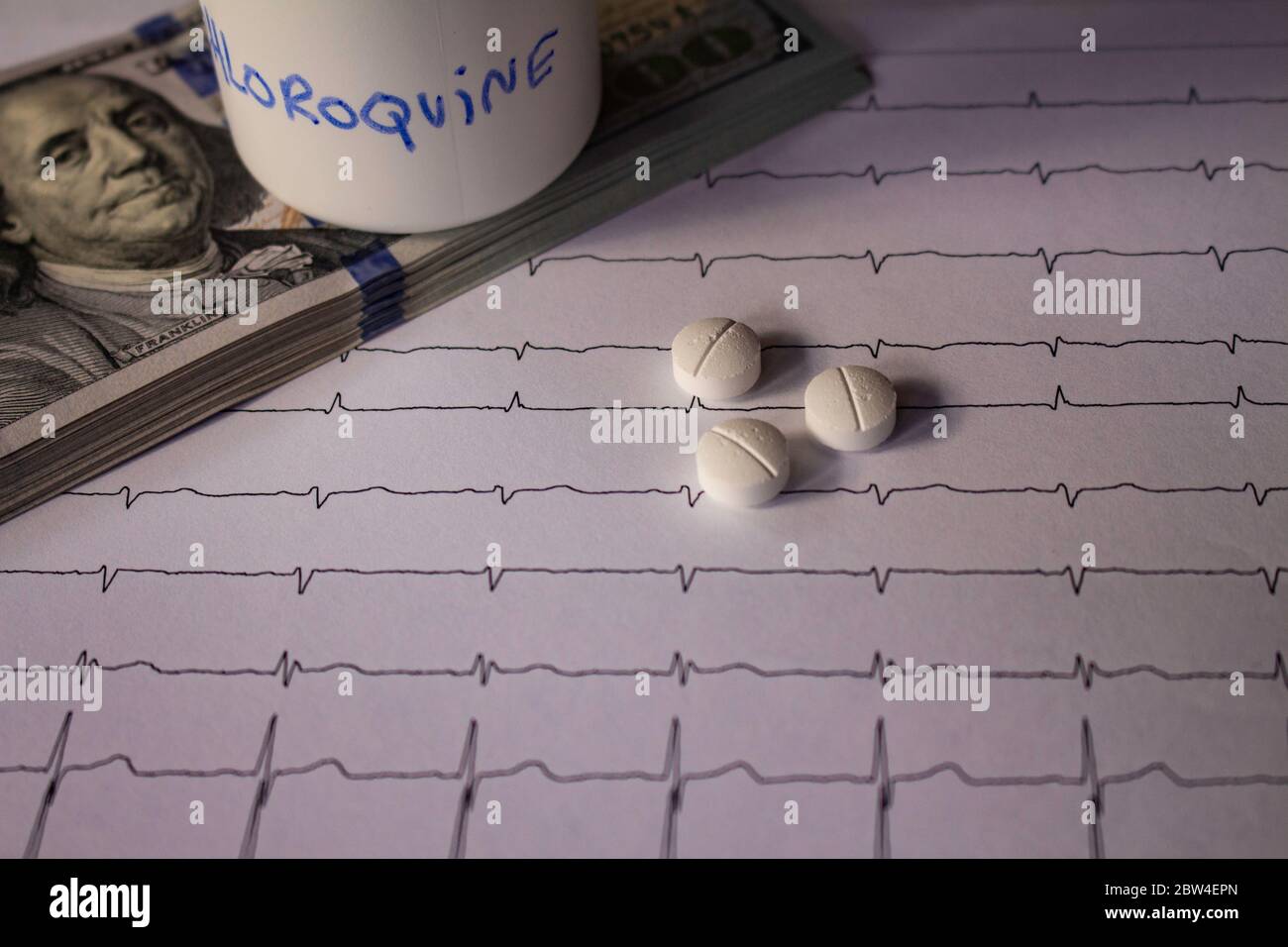 Pillole su un elettrocardiogramma. Cento dollari di bollette su un EKG. Contenitore bianco con 'idrossiclorochina' scritto sul lato. Concetto di costo elevato di Foto Stock
