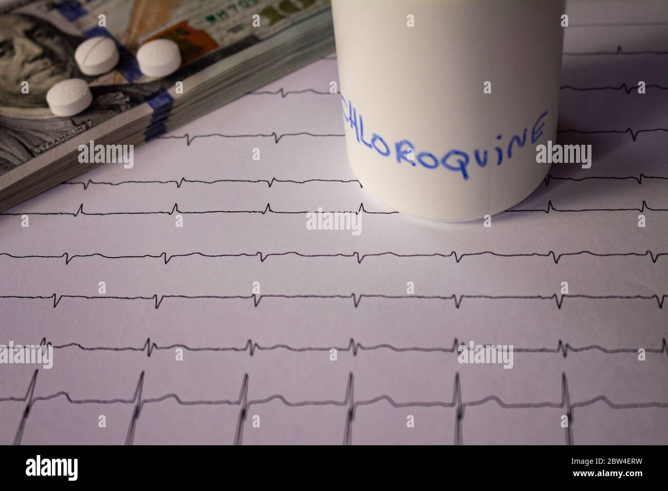 Pillole su un elettrocardiogramma. Cento dollari di bollette su un EKG. Contenitore bianco con 'idrossiclorochina' scritto sul lato. Concetto di costo elevato di Foto Stock