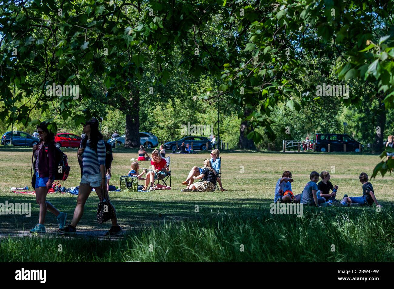 Londra, Regno Unito. 29 maggio 2020. Le madri cercano di raggiungere una distanza sociale lasciando che i loro figli giochino da vicino e condividano il cibo, Dimostrare confusione sulle regole - le persone godono del sole su Clapham Common dopo che il governo ha allentato le restrizioni e permesso alle persone di incontrarsi - Lambeth Consiglio hanno sostituito i segni per dire stare attenti e per permettere alle persone di sedersi sulle panchine. Il "blocco" dei morti continua per l'epidemia di Coronavirus (Covid 19) a Londra. Credit: Guy Bell/Alamy Live News Foto Stock