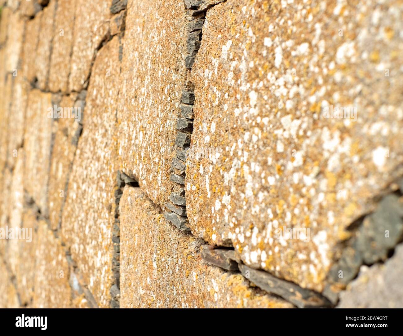 Vecchio muro fatto di pietra arenaria piatta, vista persecutiva. Foto Stock