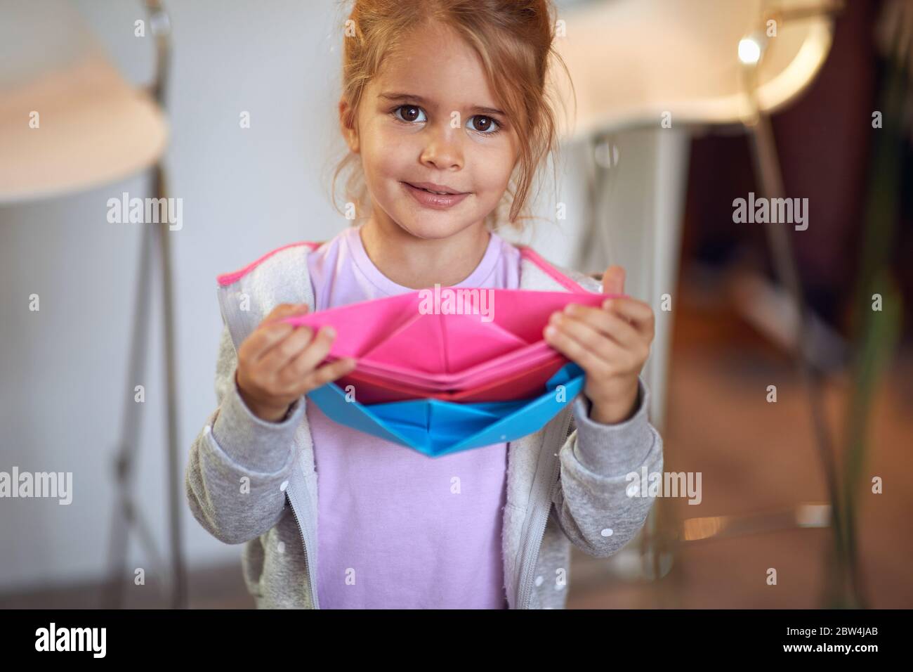 carino bambina che gioca con barche di carta. Foto Stock