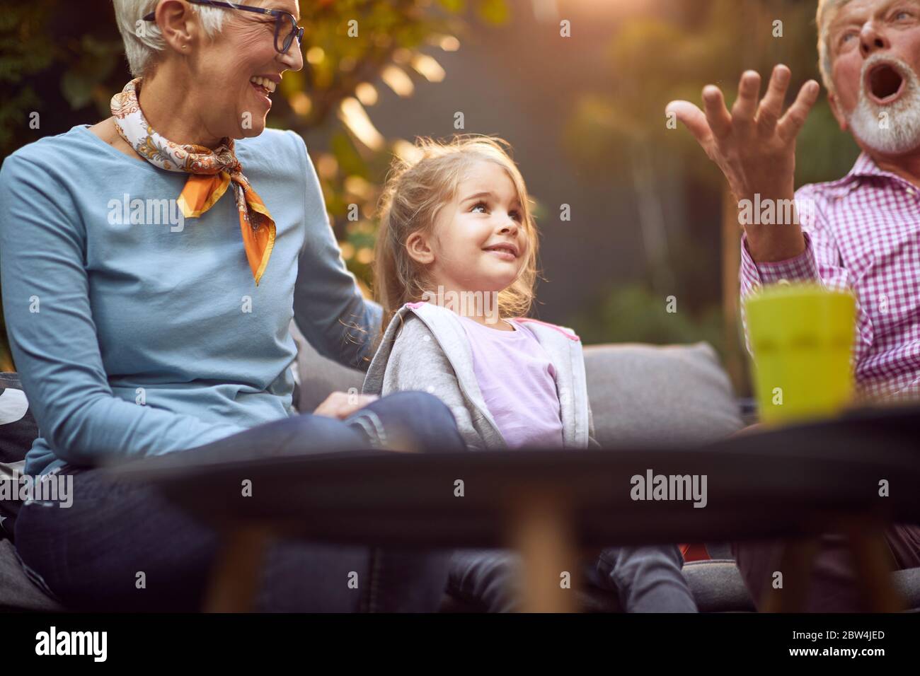 Nonni che giocano con la nipote.Girl sorridente godendosi con i suoi nonni all'aperto a casa. Foto Stock