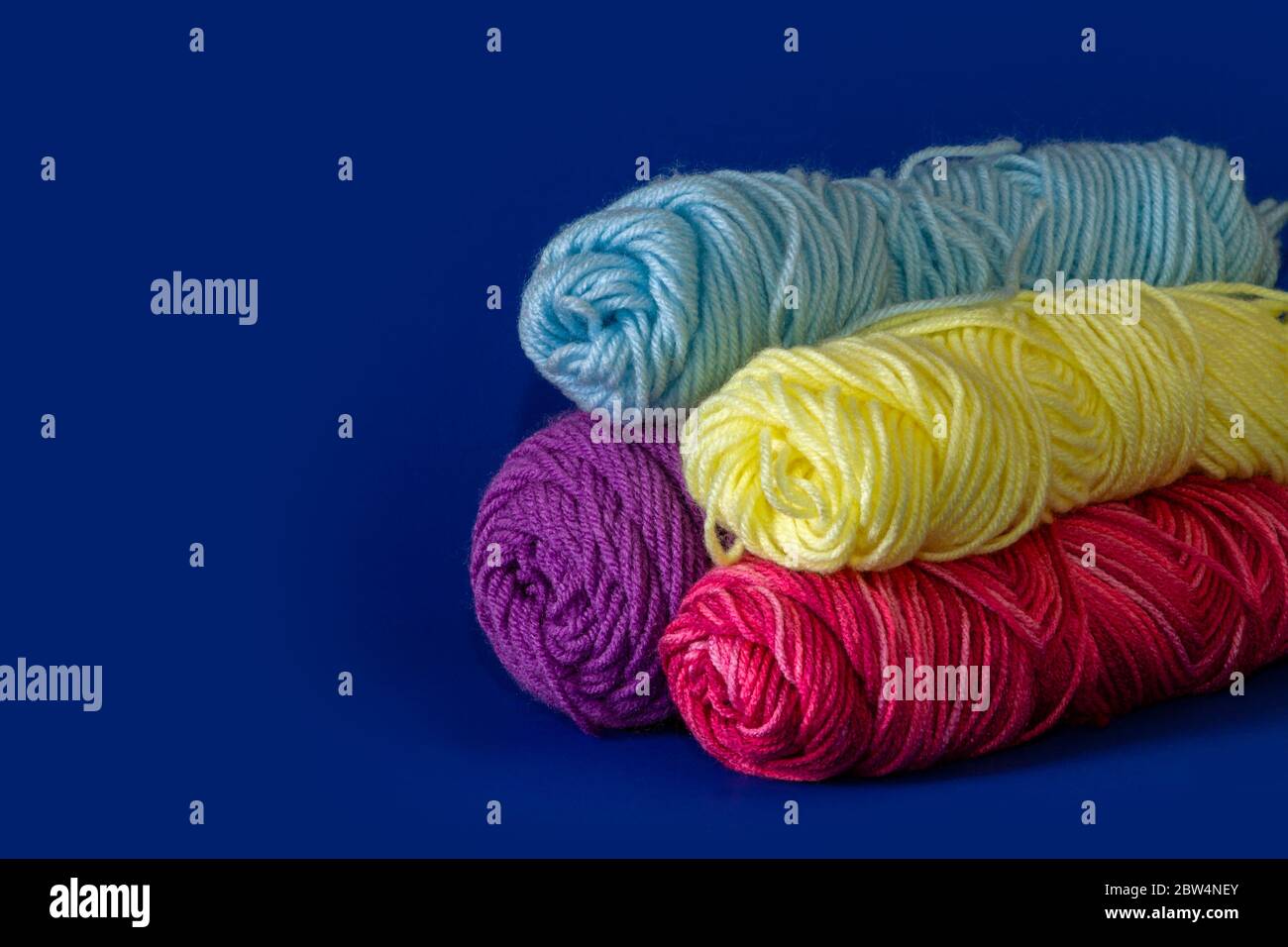 Pila di filo blu, giallo, viola e rosso con sfondo blu scuro Foto Stock