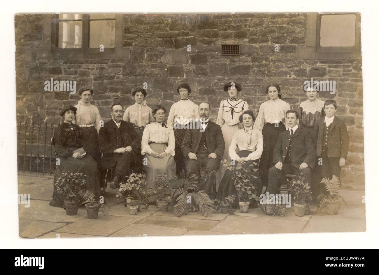 Originale inizio del 1900 's cartolina edoardiana di lavoratori vestito elegantemente Blackburn, forse il personale di ufficio del mulino di cotone, posando fuori del loro edificio di ufficio, con vasi di fiori, pubblicato 27 settembre 1904, Blackburn, Lancashire, Inghilterra, Regno Unito Foto Stock