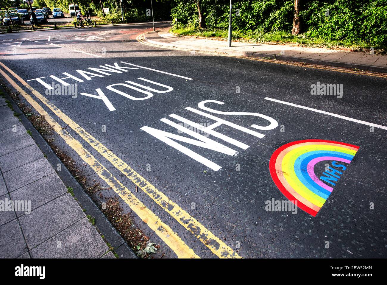 Segnaletica stradale dipinta di recente grazie NHS e un arcobaleno sono stati dipinti fuori di un centro medico a Manchester per ringraziare tutto il personale di prima linea NHS. Foto Stock