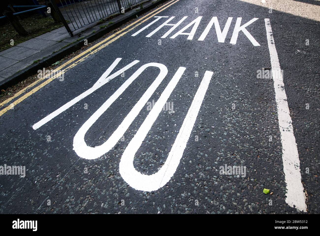 Segnaletica stradale dipinta di recente grazie NHS e un arcobaleno sono stati dipinti fuori di un centro medico a Manchester per ringraziare tutto il personale di prima linea NHS. Foto Stock