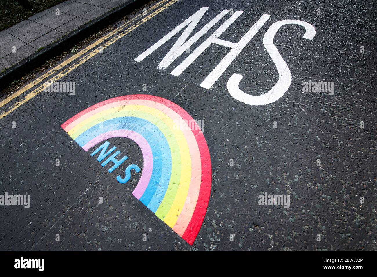 Segnaletica stradale dipinta di recente grazie NHS e un arcobaleno sono stati dipinti fuori di un centro medico a Manchester per ringraziare tutto il personale di prima linea NHS. Foto Stock