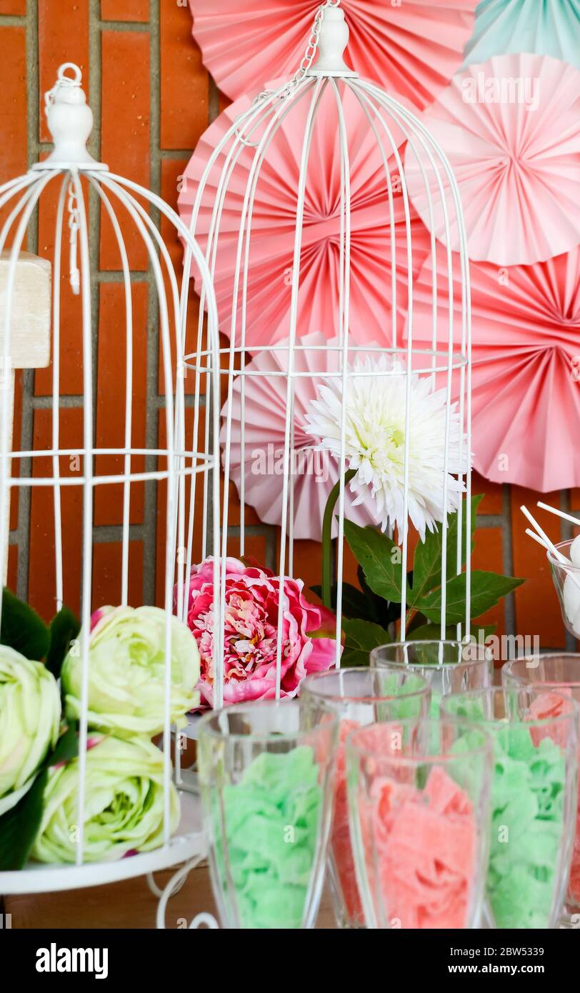 Gabbia di metallo bianco con un fiore bianco e un altro fiore rosa tra le decorazioni colorate di una festa. Foto Stock