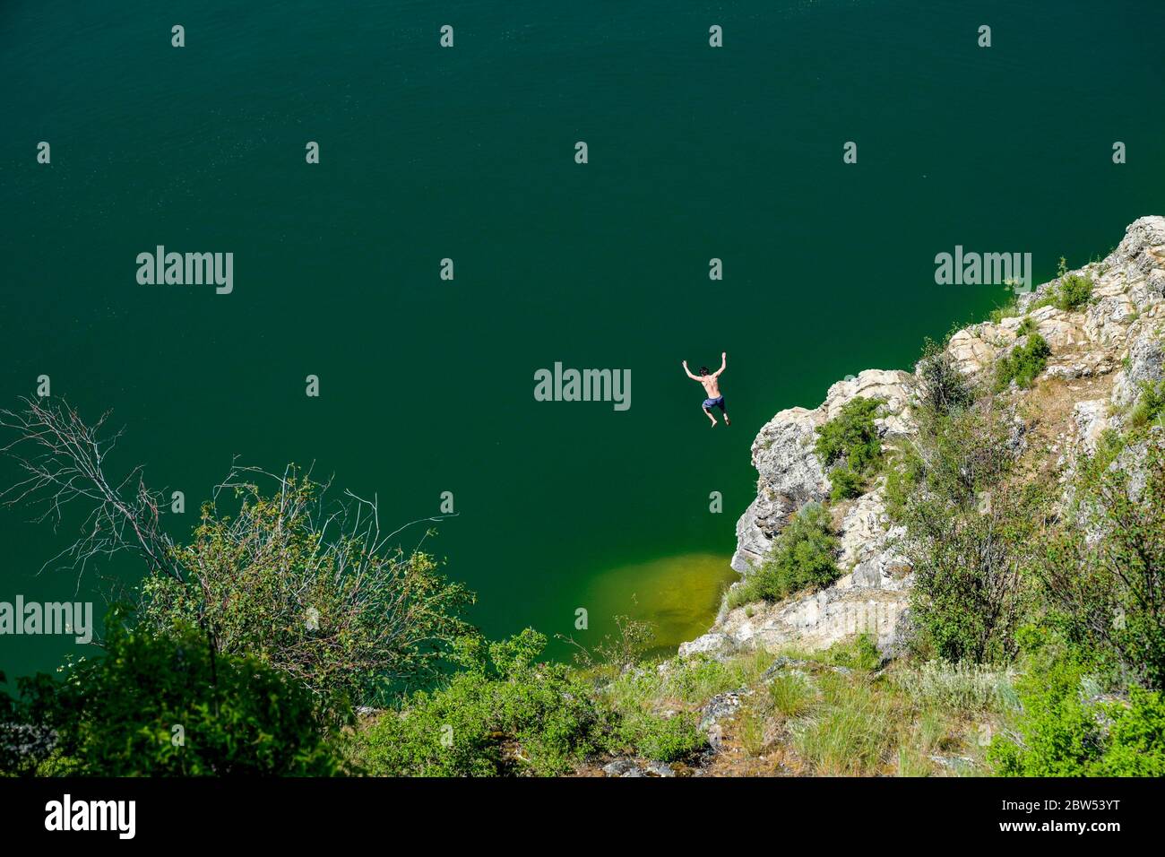 Un giovane uomo salta dalla scogliera al lago Kalamalka, al Kalamalka Lake Provincial Park, Vernon, British Columbia, Canada Foto Stock