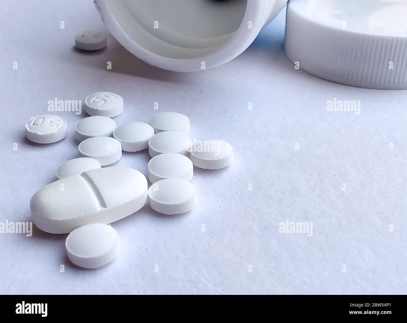 Pillole fuoriuscite dal flacone di pillola e isolate su sfondo bianco. Vista dall'alto con spazio per la copia. Concetto di medicina Foto Stock