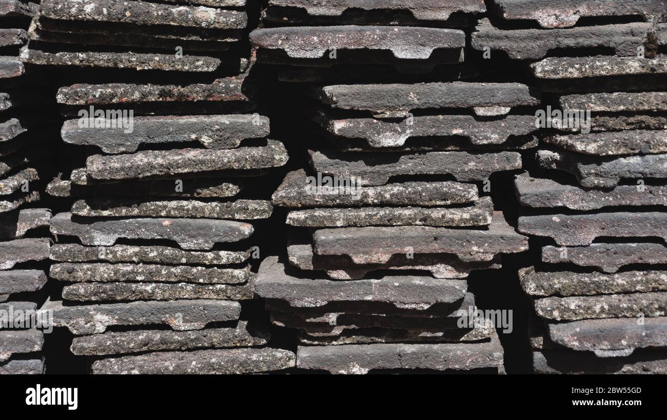 Piastrelle di tetto di cemento usurato accatastate in pile Foto Stock