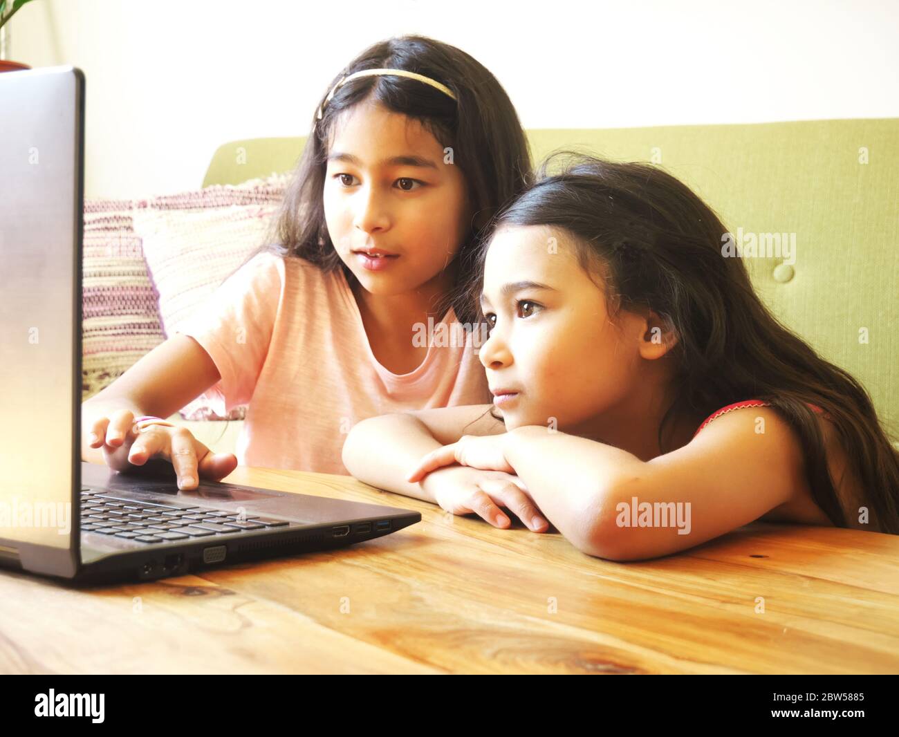 Due ragazze di Métis di età compresa tra 7 e 9 anni guardano le immagini sullo schermo di un computer portatile Foto Stock