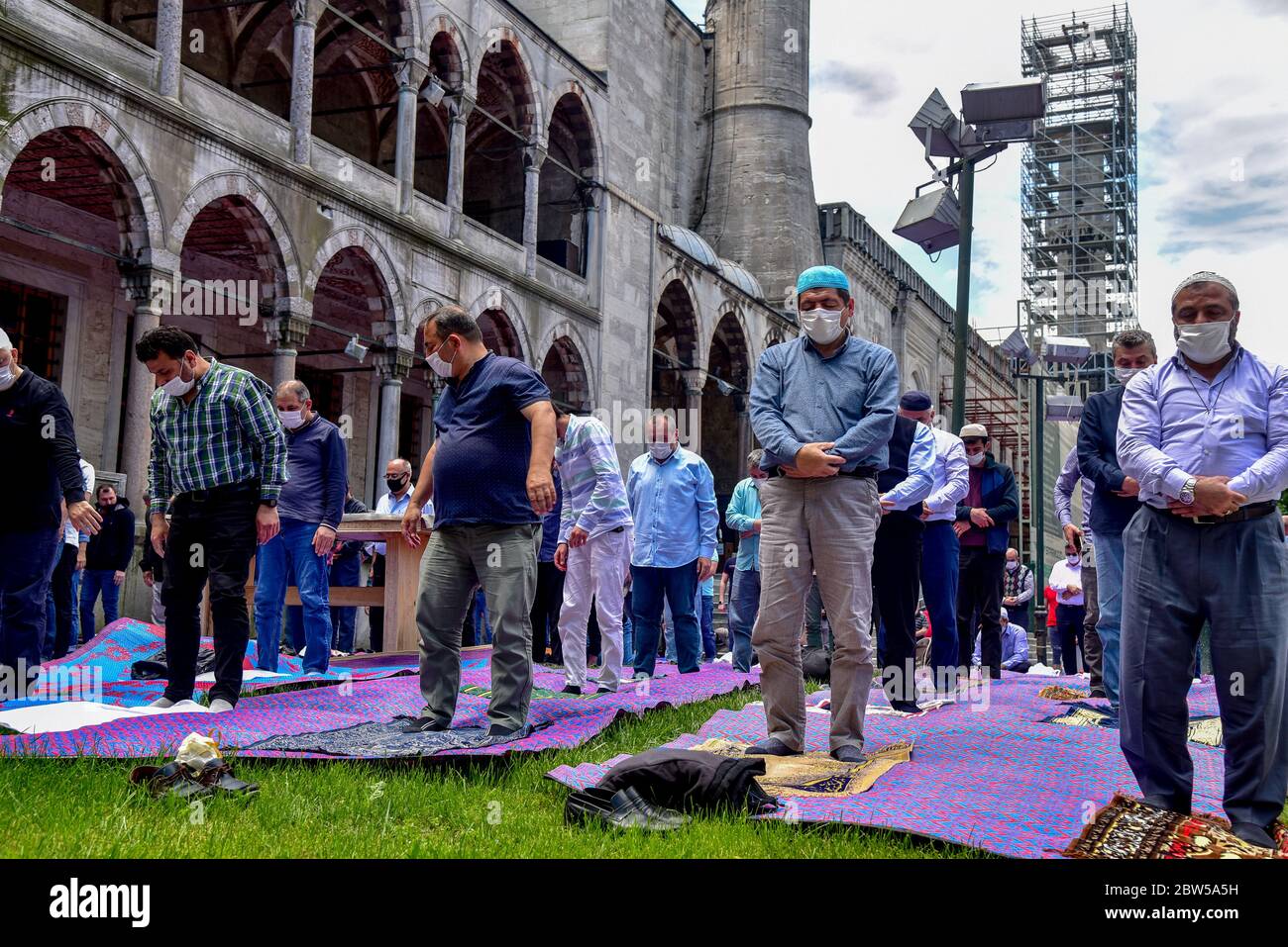 Pregare con maschere mediche fuori della Moschea Blu. Il primo venerdì pregate, namaz dopo la chiusura a Istanbul. I musulmani pregano insieme per la guarigione Foto Stock