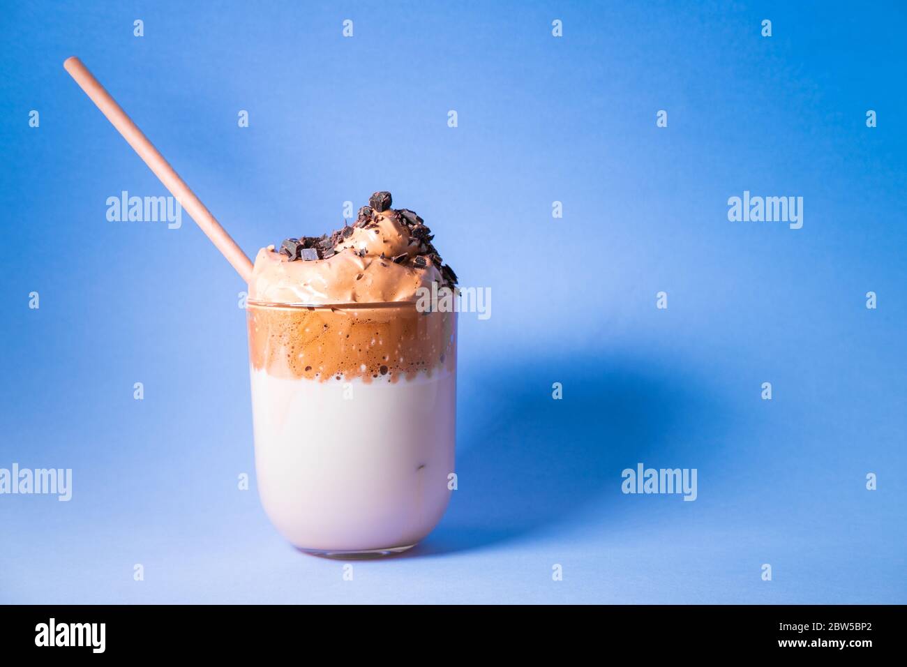 Caffè coreano Dalgona con latte e gocce di cioccolato su sfondo blu. Spazio di copia. Foto Stock