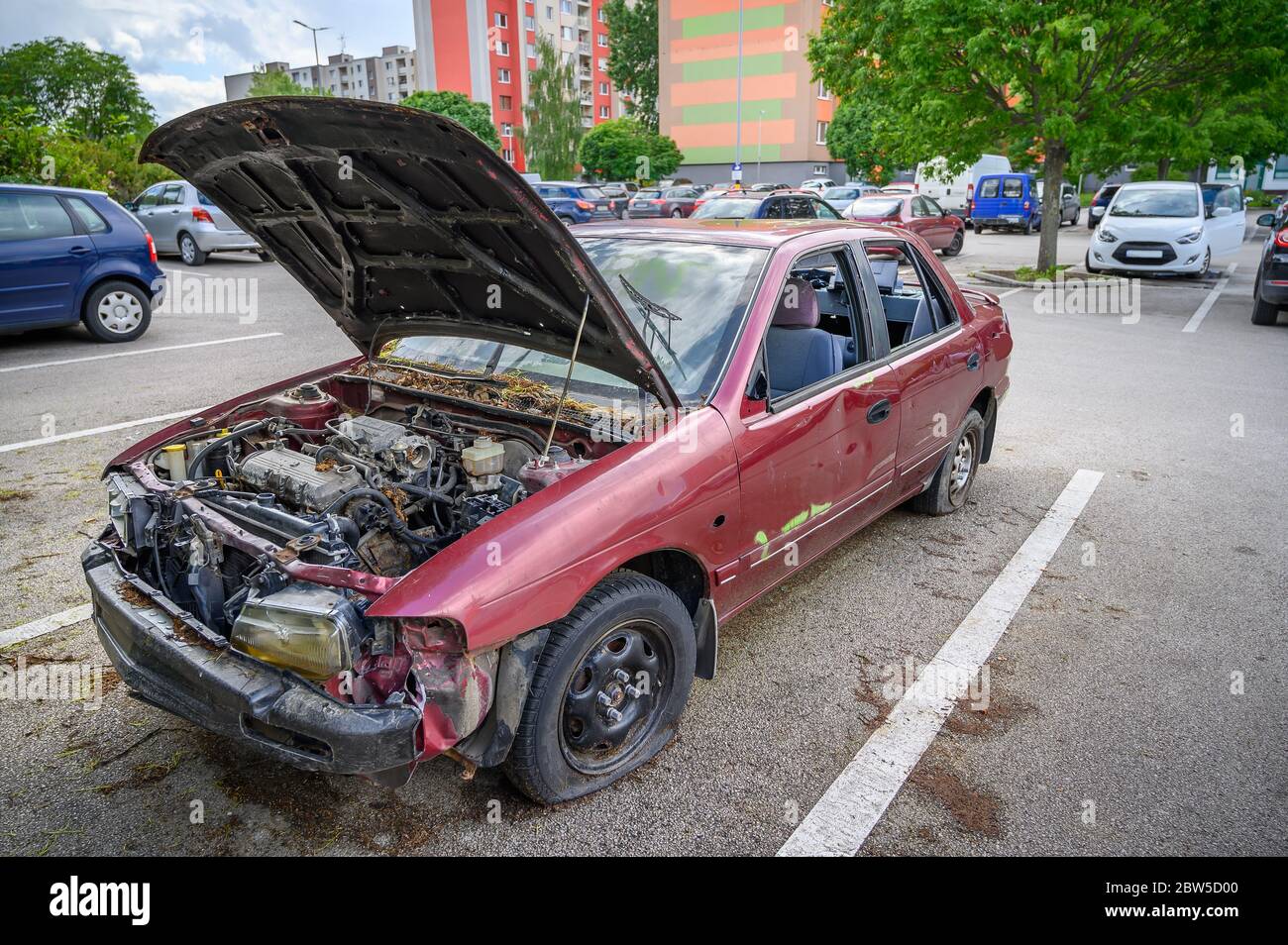Auto abbandonata distrutta con cofano aperto nel parcheggio Foto Stock