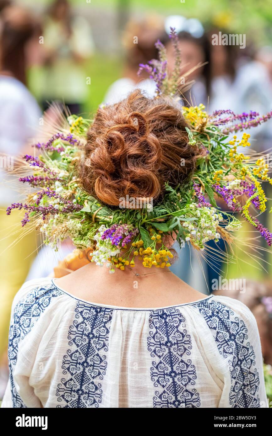 Donne non identificate in abiti tradizionali con solstizio estivo in fiori da campo, erbe e cereali. Foto Stock