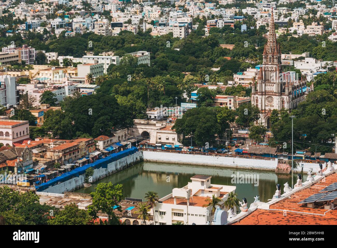 Chiesa cattolica di nostra Signora di Lourdes, accanto ad un tempio indù lago, a Tiruchirappalli, India Foto Stock