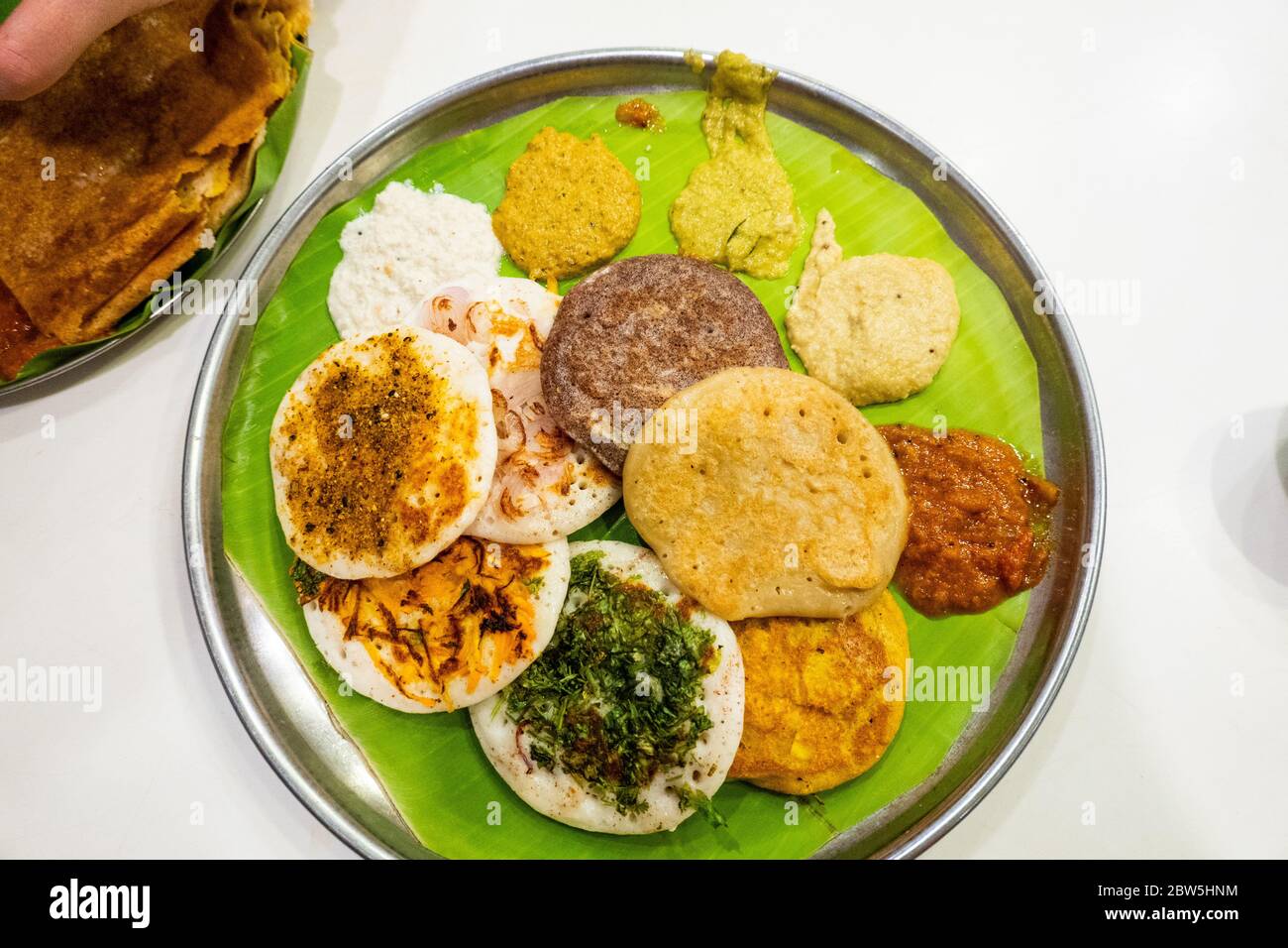 Una selezione di mini uttapam (dosa spessa) e salse chutney serviti in un ristorante a Tamil Nadu, India Foto Stock