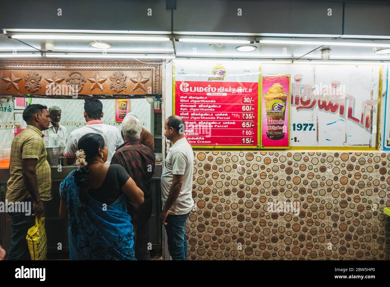 La gente del posto coda per la famosa bevanda di jigarthanda di Madurai, ingredienti che includono tipicamente ghiaccio, sciroppo di radice di sarsaparilla, zucchero e latte. Foto Stock