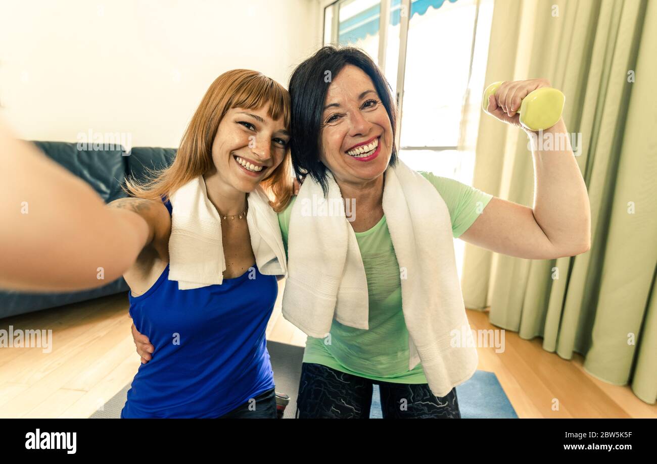 Madre e figlia felici che prendono una palestra di allenamento selfie a casa durante la quarantena. Concetto di persone, famiglia, palestra a casa, sport. Foto Stock