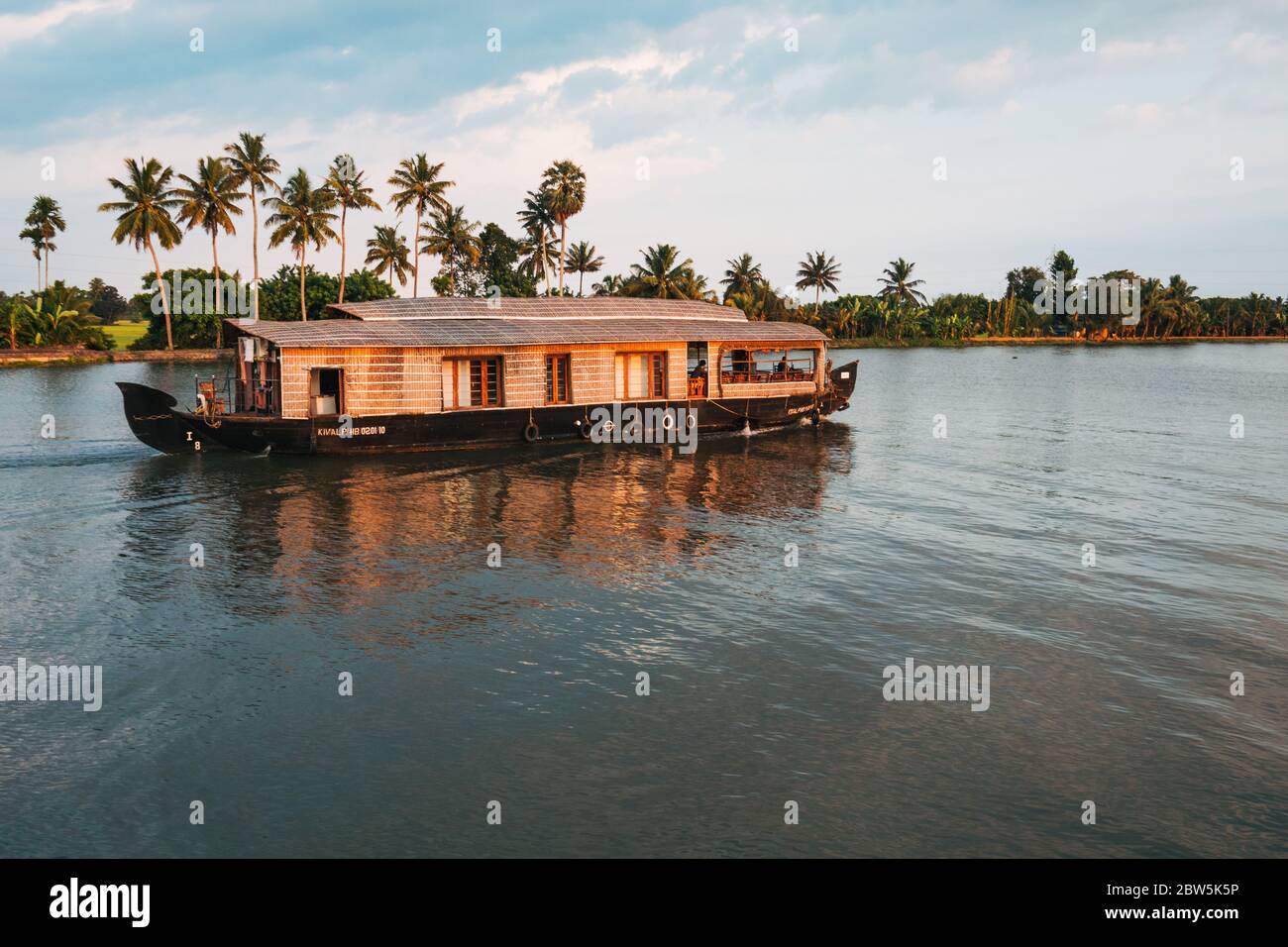 Una casa galleggiante naviga lungo un canale nel Kerala backwaters al sole di sera Foto Stock