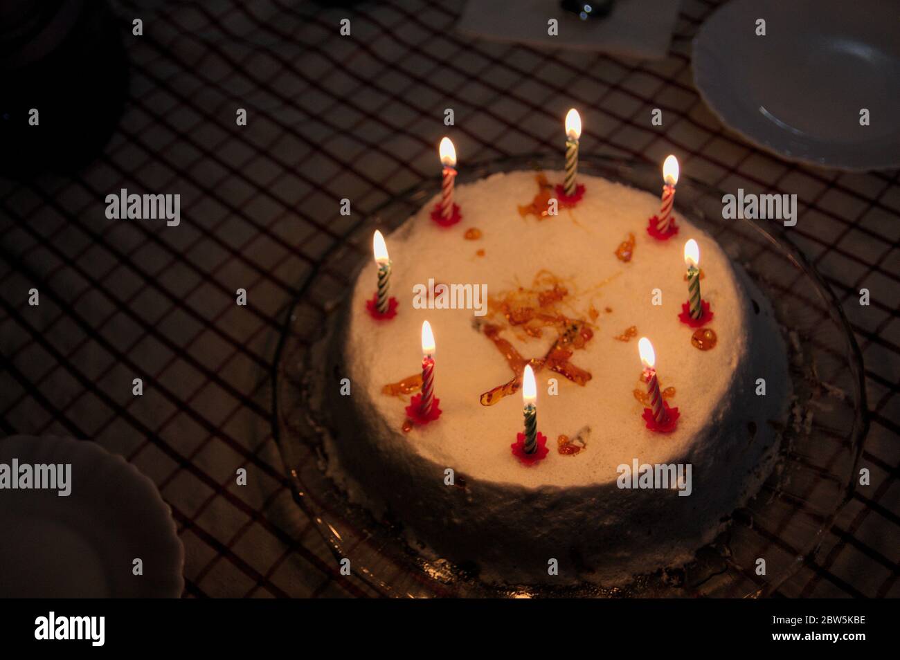 Una torta di compleanno decorata con candele accese in un ambiente senza illuminazione diversa dalle candele stesse Foto Stock