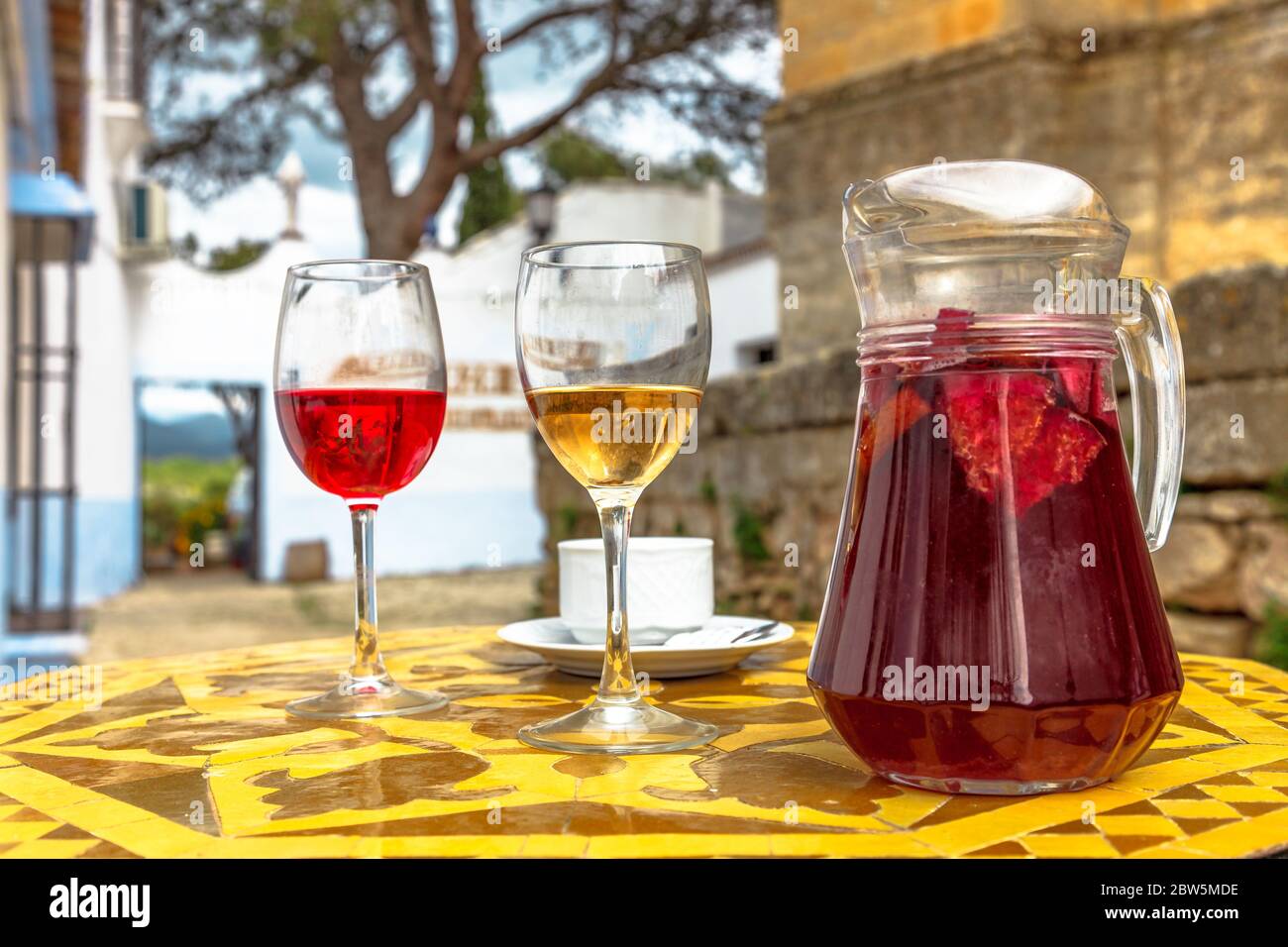 Brocca di sangria con vetri rossi e bianchi su un paesaggio spagnolo offuscato in Spagna. Foto Stock