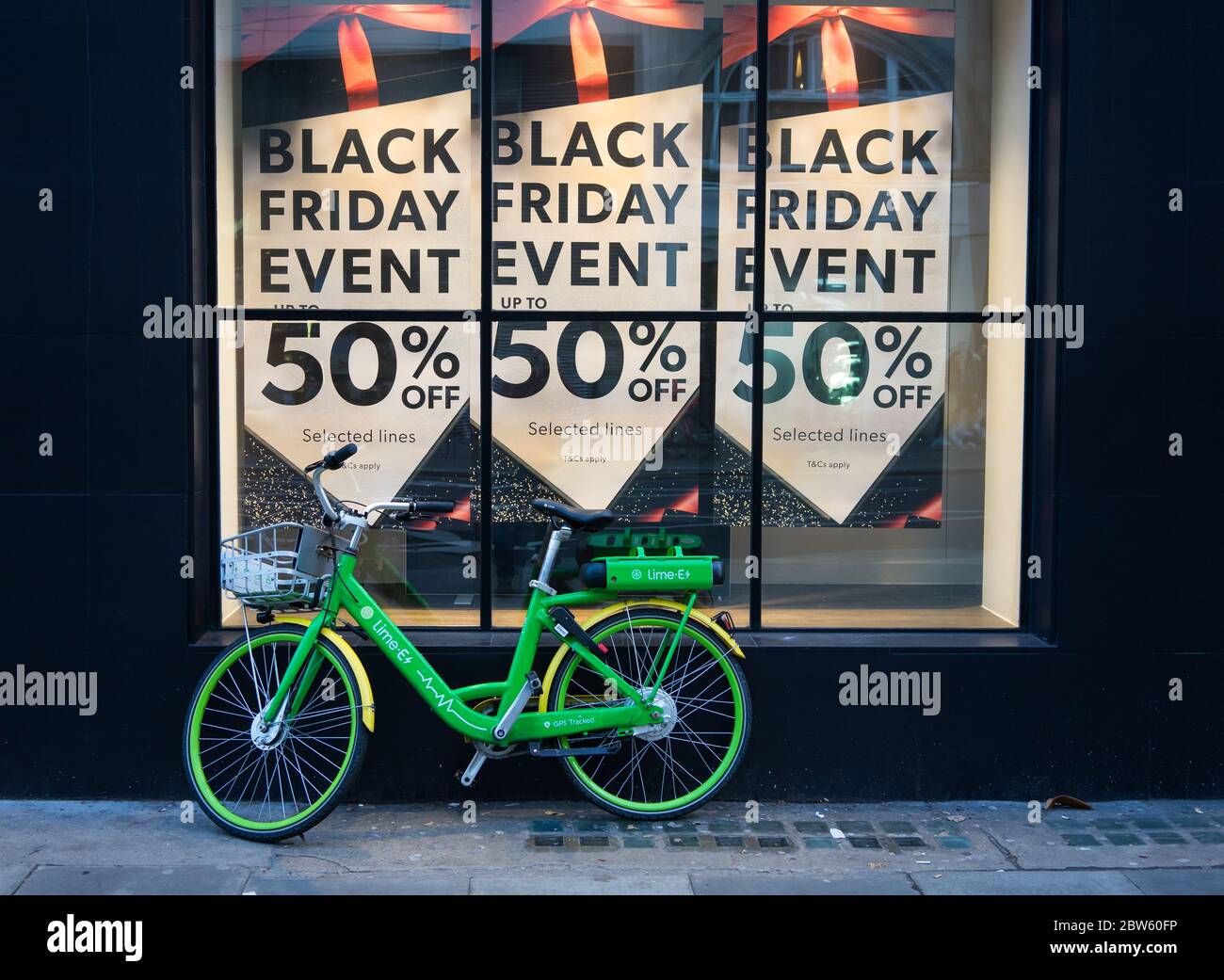 Cartello vendita Black Friday in una vetrina con un ciclo di noleggio elettronico verde appoggiato alla finestra. Londra Foto Stock