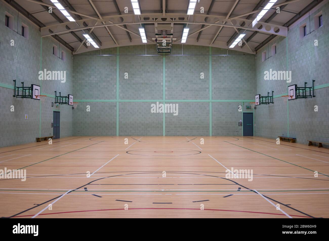 Grande sala sportiva con pareti grigie e verdi con reti da basket laterali. Foto Stock