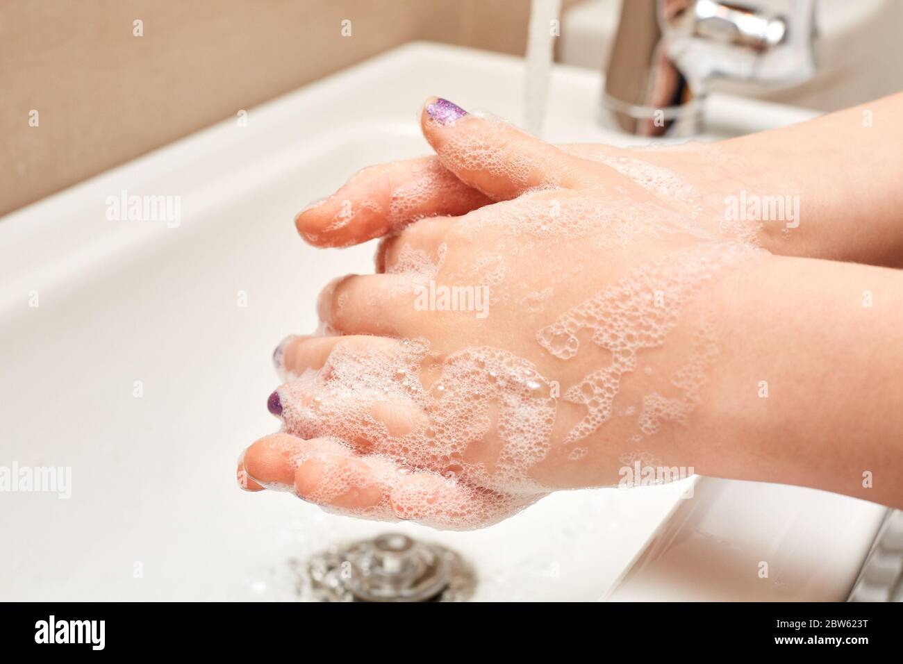 Bambino bianco lavando le mani con sapone e acqua corrente sopra il lavandino Foto Stock