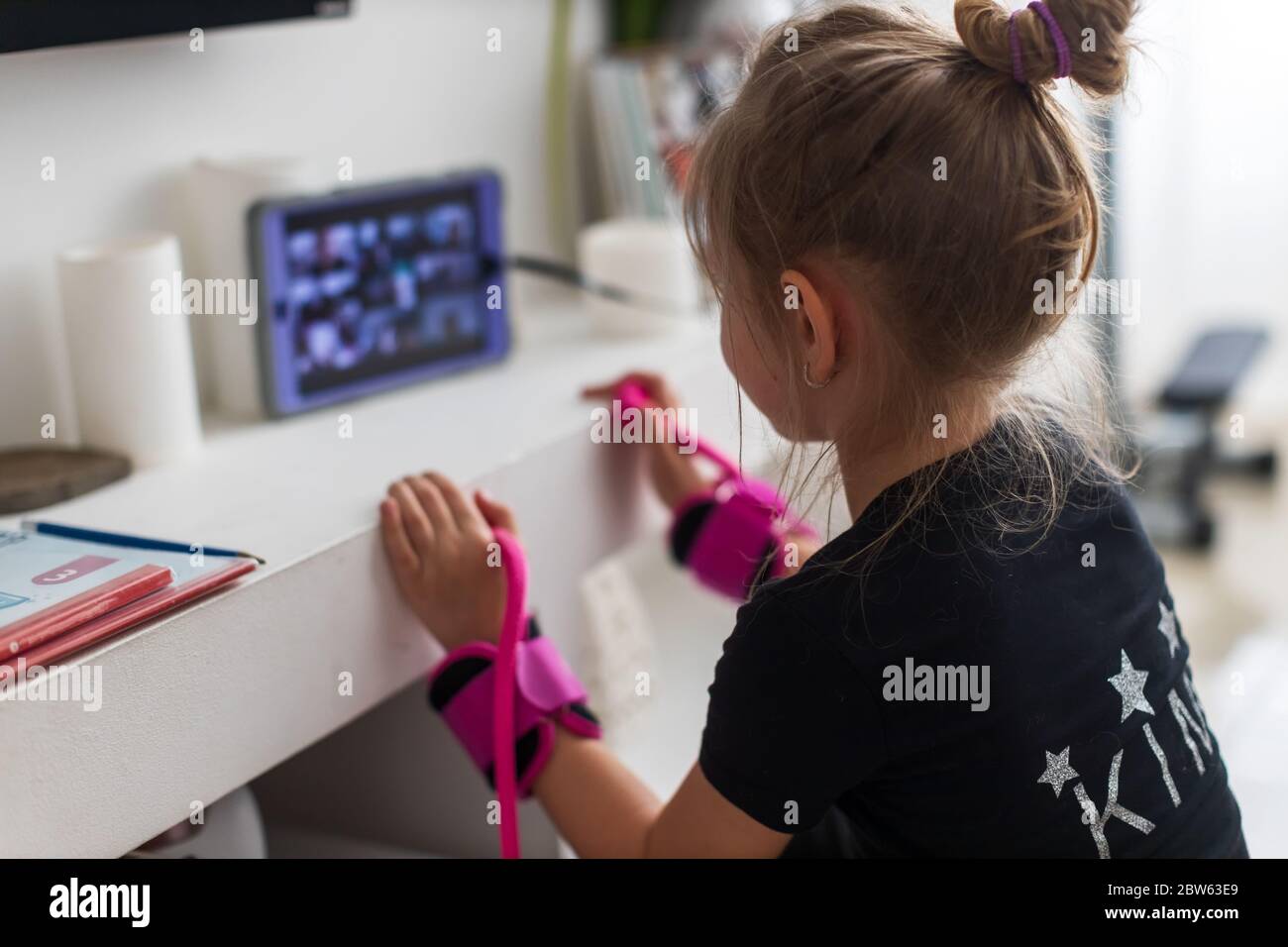 Bella ragazza giovane in sportswear guardando video online su computer portatile e facendo esercizi di fitness a casa Foto Stock