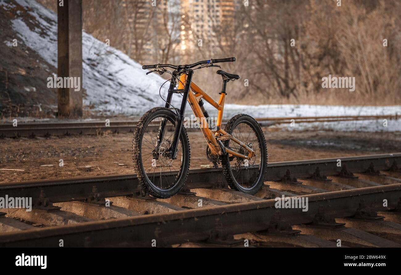 Bella mountain bike giallo si erge su rotaie, sullo sfondo di strada nevosa Foto Stock