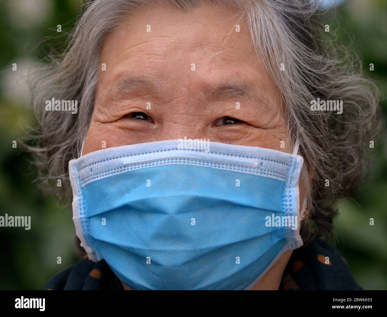 Anziana donna vietnamita indossa una maschera chirurgica monouso durante la pandemia del virus corona 2019/20. Foto Stock